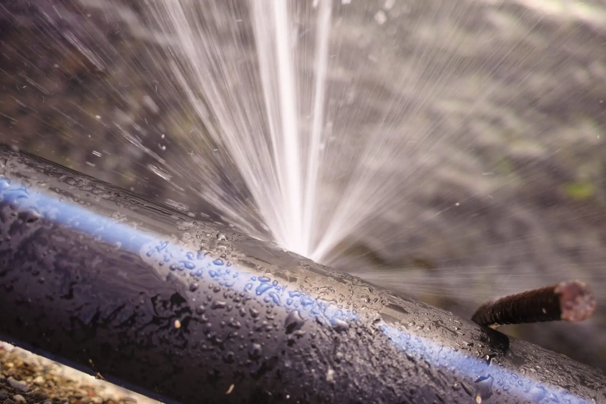 Burst pipe spraying water, illustrating Birmingham AL leak repair services.
